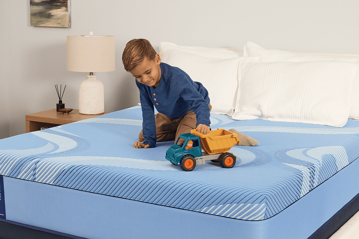 boy playing with his toy dump truck on a sealy mattress