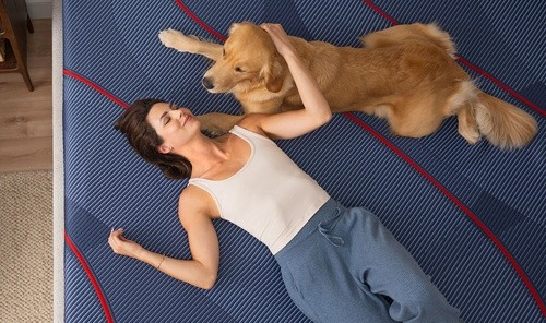 A woman and dog lying on a mattress