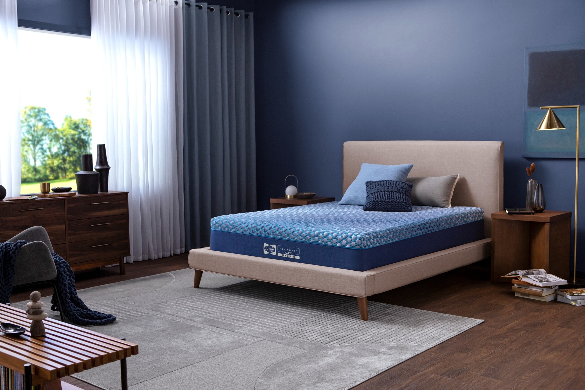Sealy FlexGrid blue mattress sitting in a room with blue walls a grey rug and wood furniture