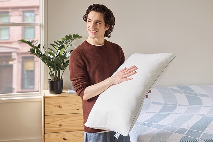 a young man holding a sealy pillow