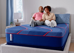 Man and woman laying on a Posturepedic Elite Hybrid mattress in a styled room