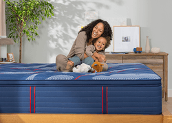 Woman and child sitting on a Elite spring mattress with a pillow top - mobile