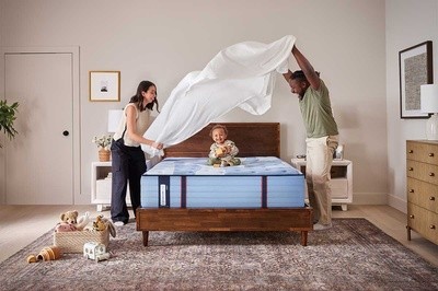A family putting sheets on a bed in a styled room