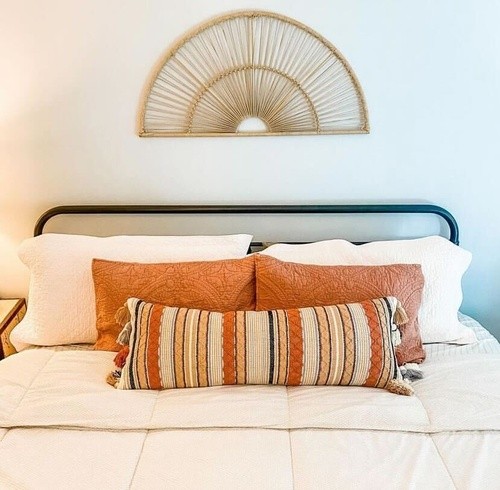 sealy mattress with orange and stripped throw pillows on a white comforter on a black metal bed frame